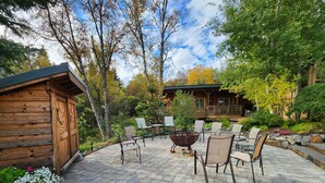 Un patio con piastrelle in pietra, mobili da esterno e un chalet in legno.
