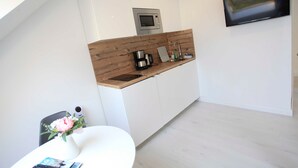 Eine moderne Küche mit weißen Schränken, einer Holz Arbeitsplatte, einer eingebauten Mikrowelle und einem an der Wand montierten Flachbildfernseher.
