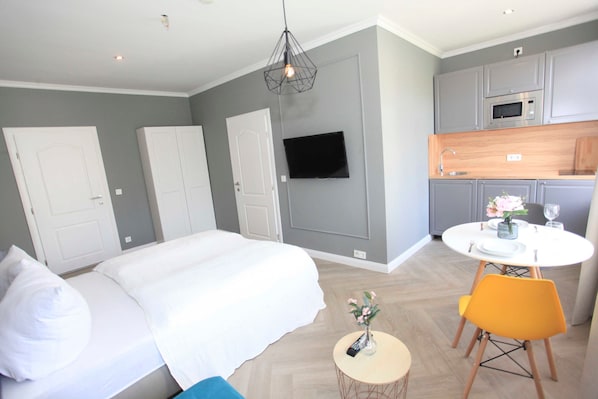 A bedroom with a bed, a bedside table with a vase, and a small round table with a chair.