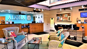 A lobby with wicker furniture, a reception desk, and a wall with the word "ALOHA".