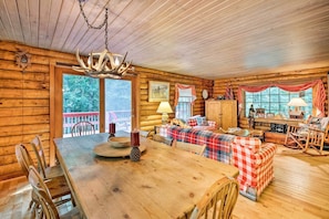 Cozy cabin-style room with a large dining table, sofa, and rocking chair, perfect for relaxing.