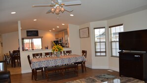 A dining area with a table set for four, a ceiling fan, and a kitchen in the background. - Colorado Getaway w/ Hot Tub & Fire-pit Sleeps 16+ (Northglenn)