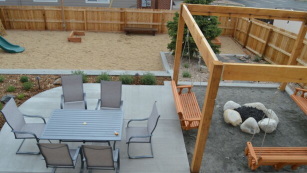 A patio with a table and chairs, a swing set, and a sandbox. - Colorado Getaway w/ Hot Tub & Fire-pit Sleeps 16+ (Northglenn)