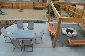 Eine Terrasse mit Tisch und Stühlen, einer Schaukel und einem Sandkasten.