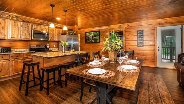 Interior de una cabaña de madera con cocina, comedor y sala de estar.