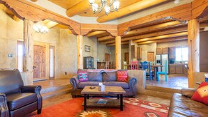 A spacious living room with a wooden ceiling, a sofa set, a coffee table, and a red carpet.