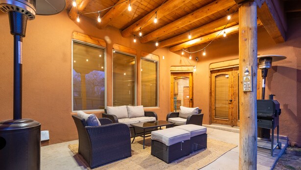 An outdoor patio with wicker furniture, a grill, and string lights.