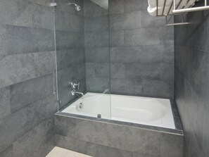 Ein modernes Badezimmer mit einer begehbaren Duschkabine aus Glas und einer freistehenden Badewanne.