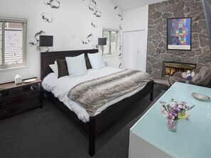 Ein Schlafzimmer mit einem großen Bett, einem Kamin aus Stein und einem modernen Kunstwerk an der Wand.