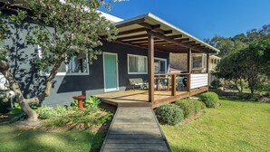 A house with a wooden deck, a green door, and a window.