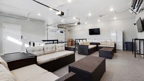 Een moderne woonkamer met een zithoek, een salontafel en een flatscreen televisie aan de muur.