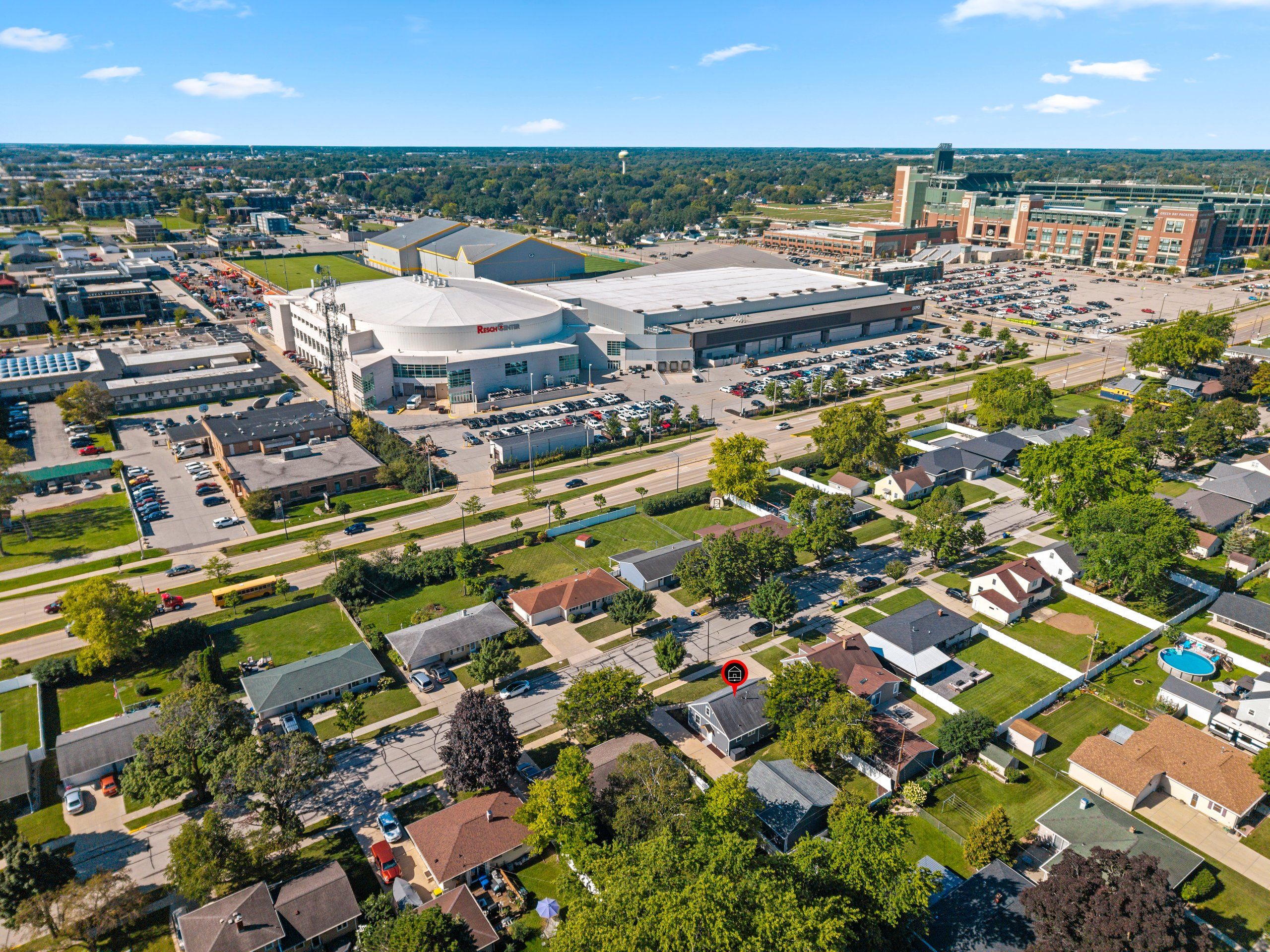 Vista aérea de una zona residencial con casas, un estacionamiento grande y un estadio deportivo.