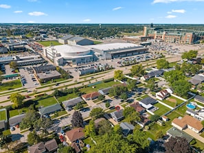 Vue aérienne d’un quartier résidentiel avec des maisons, un grand parking et un stade.