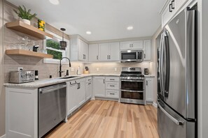 Une cuisine moderne avec des meubles gris, des appareils en acier inoxydable et un plancher en bois.