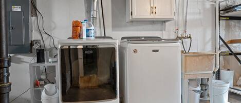 Une petite buanderie équipée d’un lave-linge, d’un sèche-linge et d’un meuble de rangement au-dessus.