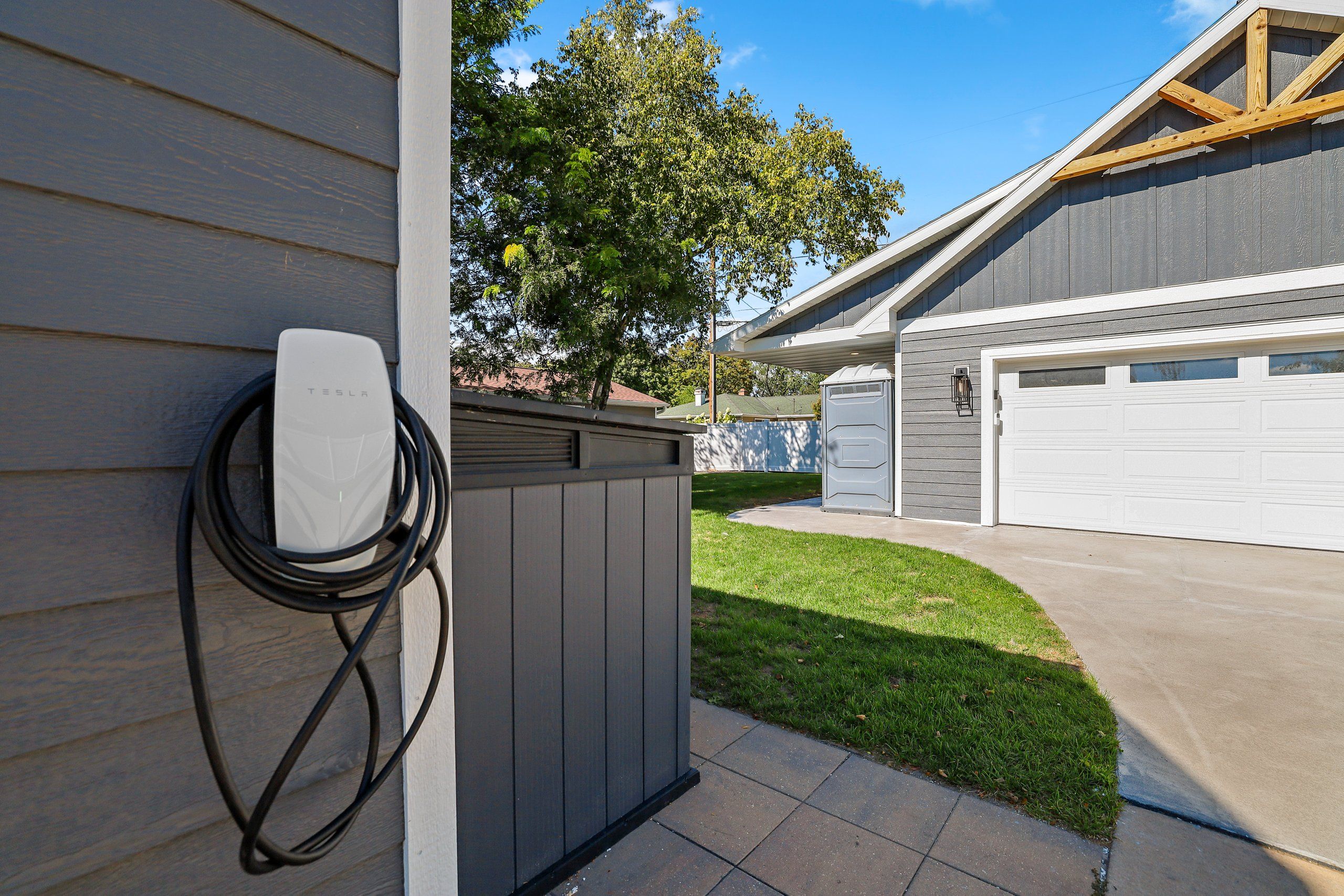 Un garaje residencial con una estación de carga para Tesla instalada en la pared exterior.