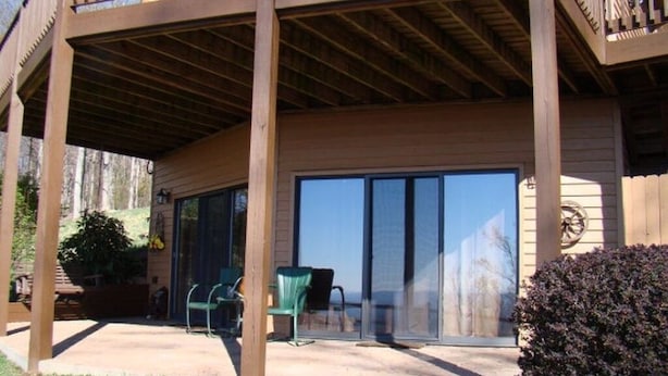 Une terrasse en bois avec un espace patio couvert, des portes-fenêtres coulissantes et des sièges d’extérieur.