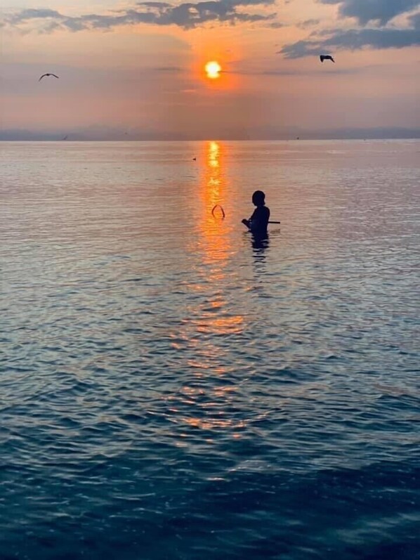 Eine Person im Wasser bei Sonnenuntergang.