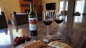 A wine bottle, two wine glasses, grapes, crackers, and cheese on a wooden board. - Quail Hollow Retreat (Sedona)