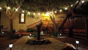 A courtyard with a fountain, a wooden staircase, and string lights. - Quail Hollow Retreat (Sedona)