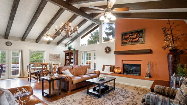 A spacious living room with a fireplace, leather sofas, and a chandelier. - Quail Hollow Retreat (Sedona)