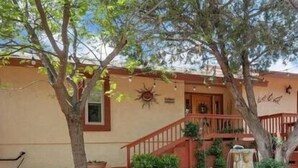 A house with a front porch, a staircase, and a garden area with plants and a fountain. - Quail Hollow Retreat (Sedona)