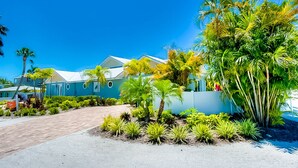 Un complexe hôtelier comprenant plusieurs bâtiments bleus, une promenade dallée et des jardins aménagés dans un style tropical.