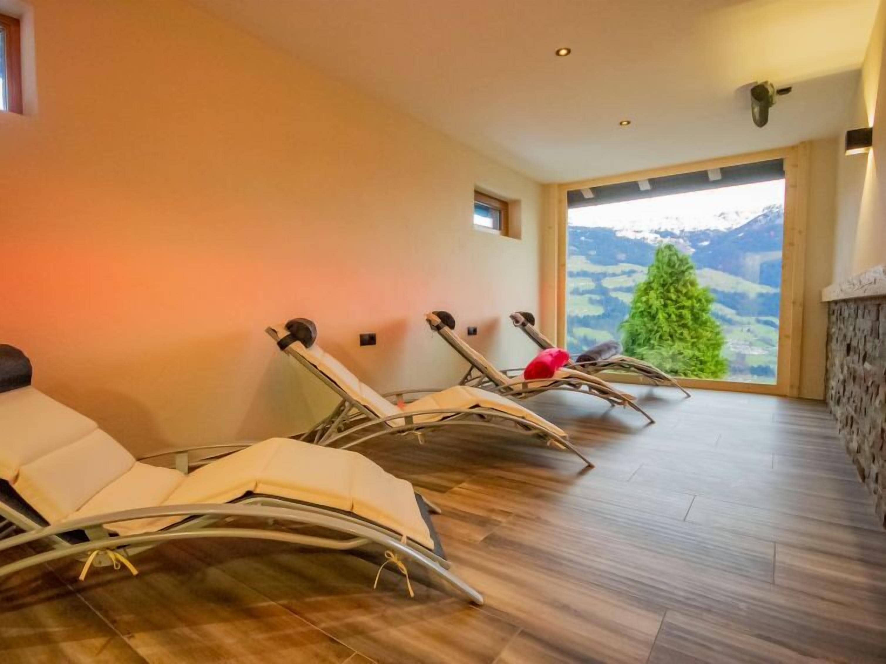 Une salle de spa équipée de fauteuils inclinables, d’une cheminée en pierre et offrant une vue sur un paysage montagneux.