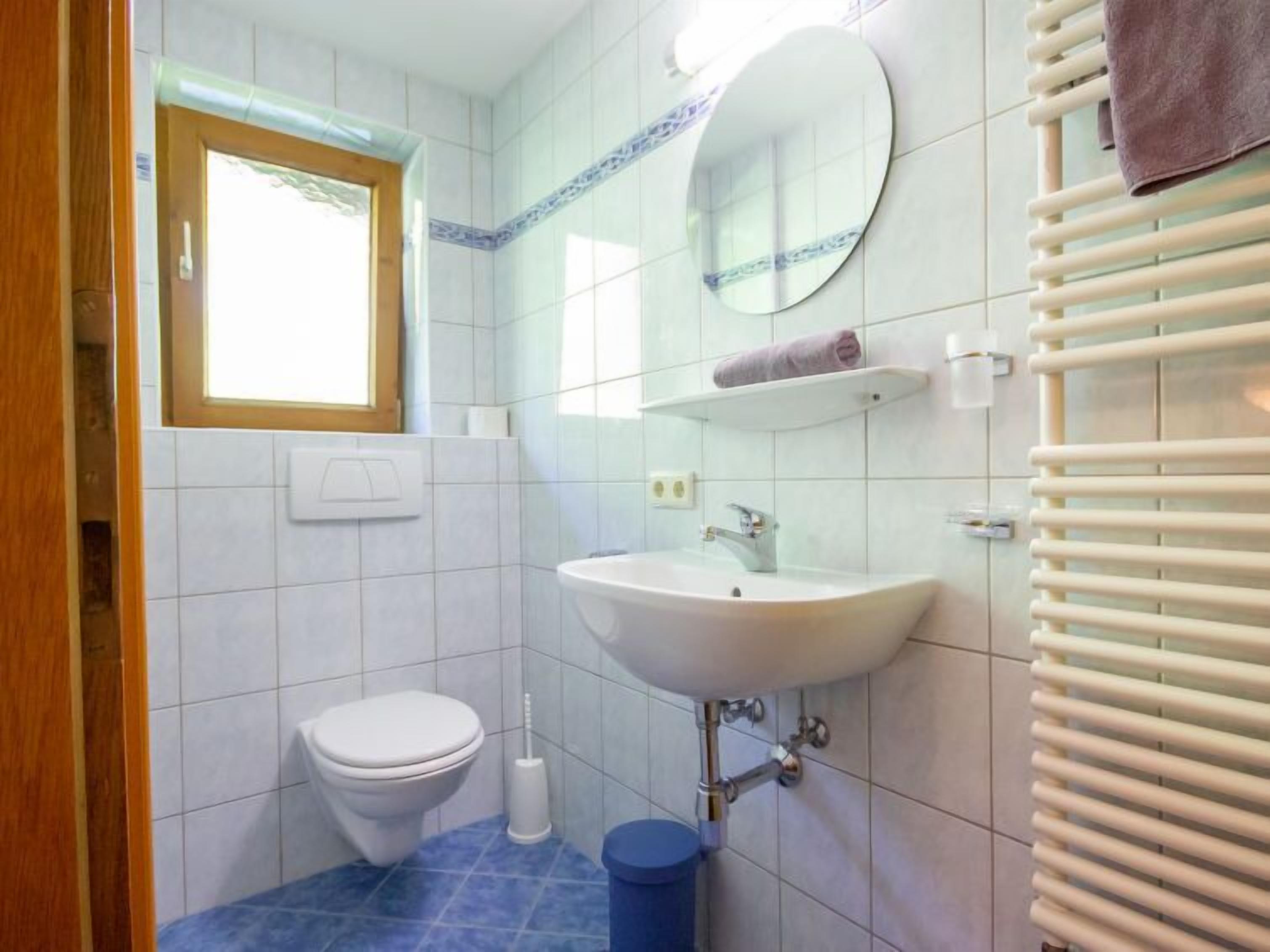 Une petite salle de bain comprenant des toilettes, un lavabo, un miroir et un porte-serviettes.