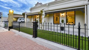 A hotel with a white facade, black iron fence, and a well-maintained lawn. - Aloha Central Premium Studios (Mount Gambier)