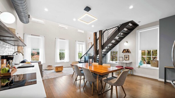 Eine moderne Küche mit Einbauofen, ein Essbereich mit Holztisch und Stühlen sowie eine Treppe, die in einen oberen Bereich führt.