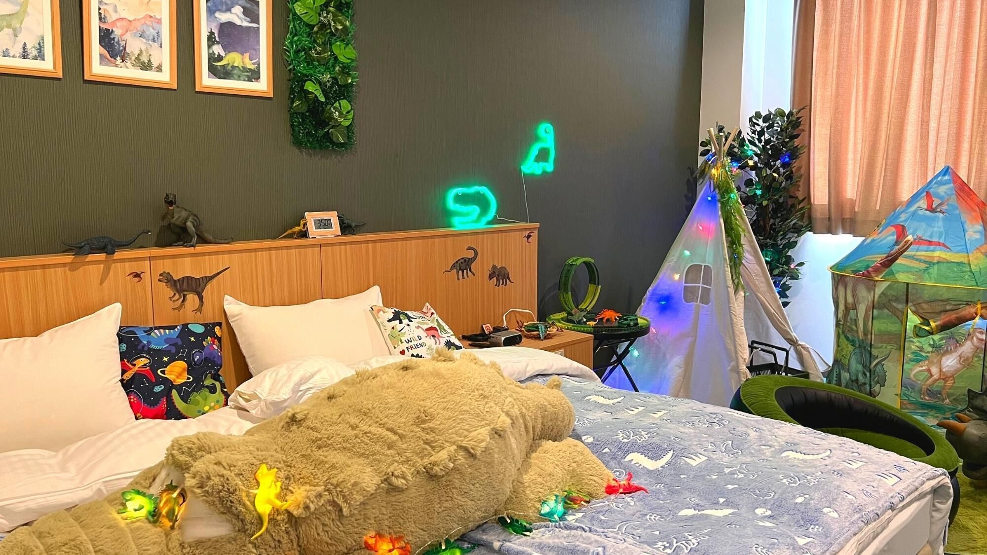 A child's bedroom with a bed, dinosaur decorations, a tent, and a clock.