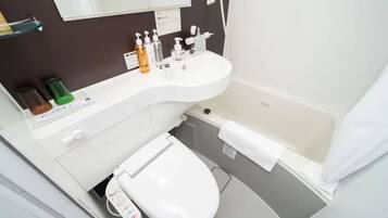 A modern bathroom with a white sink, toilet, and bathtub. There are toiletries on the sink counter.