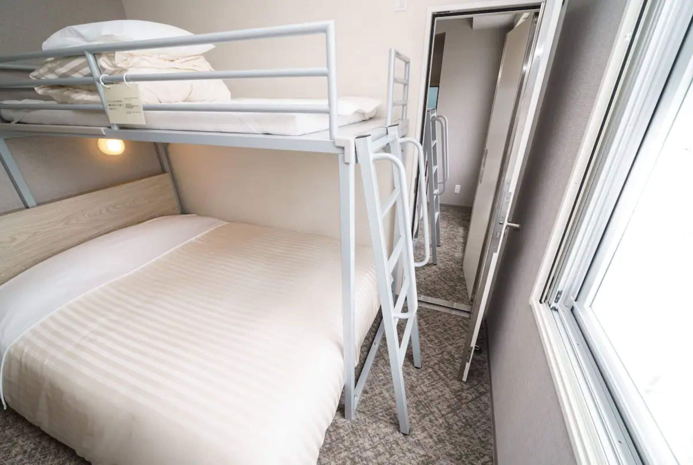 A bunk bed room with a window, a door, and a light fixture.