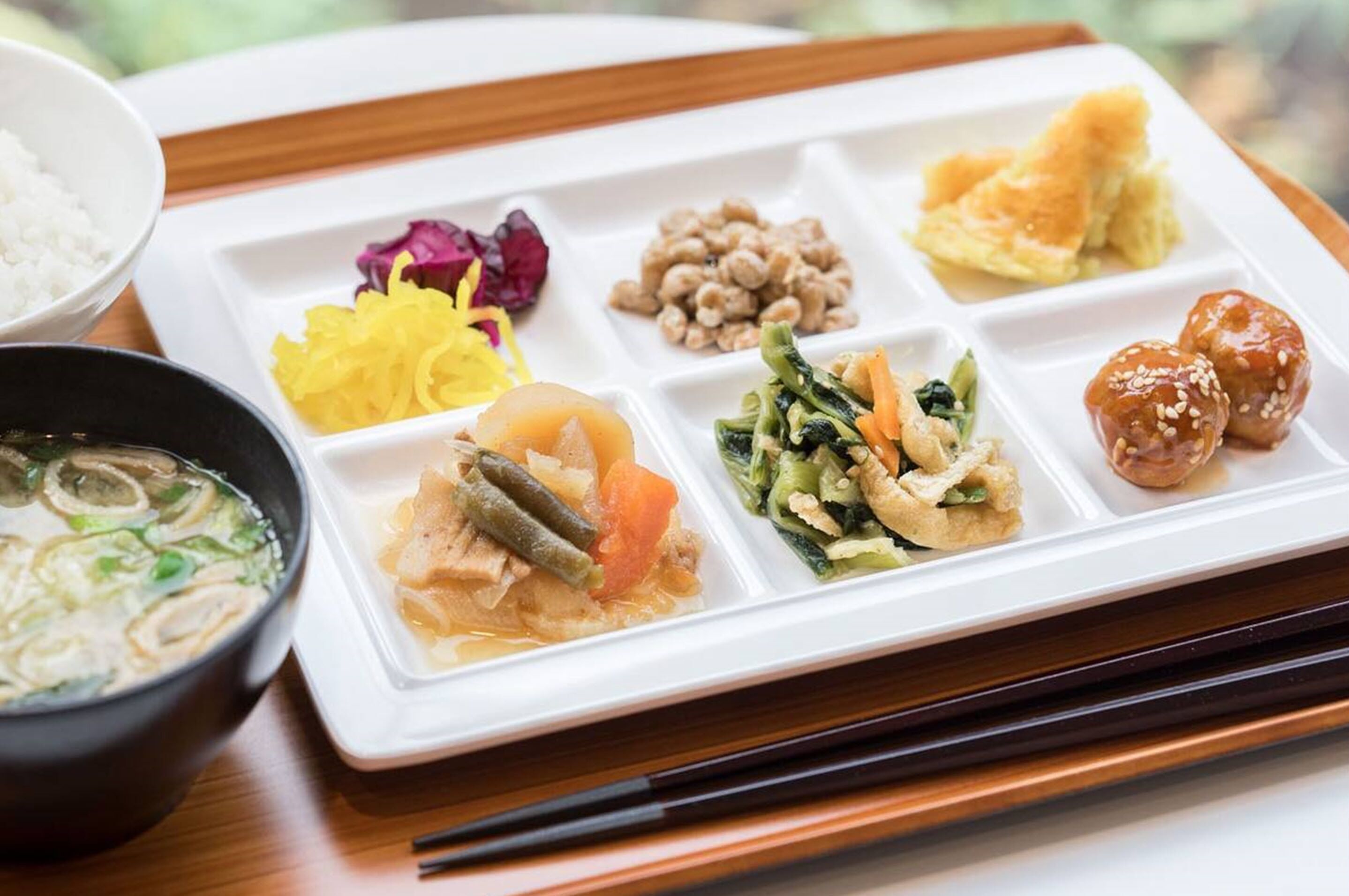 A meal with various dishes on a white tray, including a bowl of soup and a plate with multiple food items.