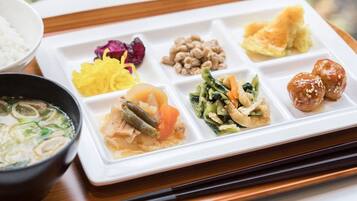 A meal with various dishes on a white tray, including a bowl of soup and a plate with multiple food items.