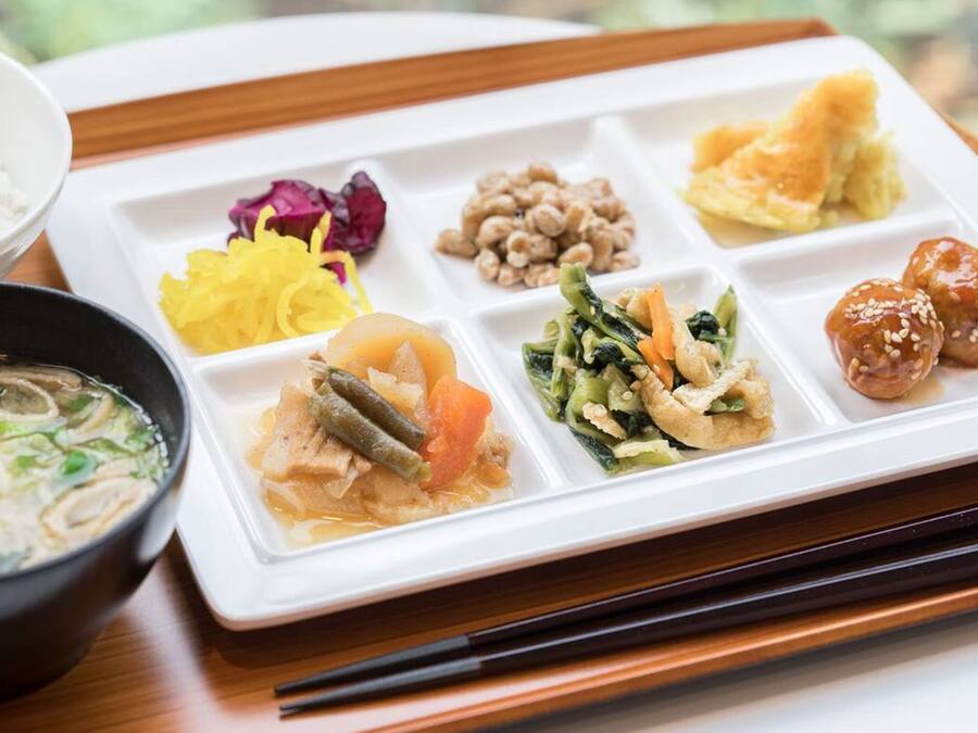A meal with various dishes on a white tray, including a bowl of soup and a plate with multiple food items.
