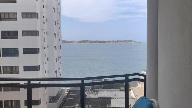 Varanda com vista para o mar, um ventilador de teto e cadeiras azuis.