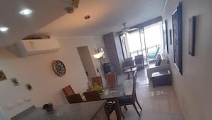 Cozinha moderna com ilha central, área de jantar com cadeiras e uma grande janela que oferece luz natural.