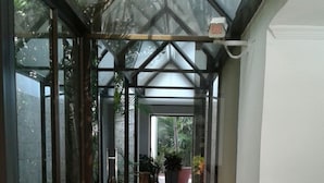 Uma galeria coberta com piso estampado, paredes de vidro e plantas em vasos.
