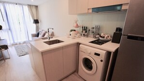 Una cocina compacta con lavadora integrada, un lavamanos y una estufa.