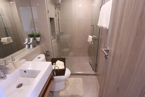 Ein modernes Badezimmer mit einer begehbaren Glasdusche, einem weißen Waschbecken und einer Toilette.