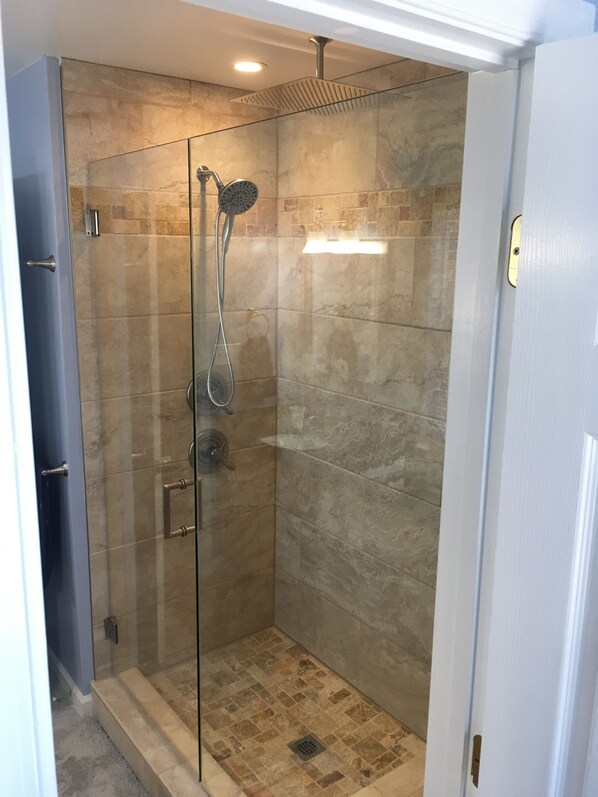 A glass-enclosed shower with a handheld showerhead and a wall-mounted rain showerhead, tiled with beige and brown tiles. - 2 Blocks to Beach, 5 Beds, Deck, Grill, Fire Pit, Stocked Kitchen, FIOS (Norfolk)