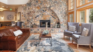 A cozy living room with a stone fireplace, leather sofa, and armchairs. - Private Balcony w/ Mountain Views in River Run, Short Walk to Everything! (Keystone)