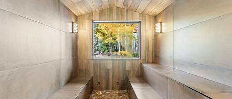 Un intérieur moderne avec un plafond en bois, un mur de verre donnant sur la forêt et un sol à motifs.