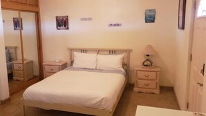 Une chambre à coucher avec un lit, deux tables de chevet, un miroir et une petite table.