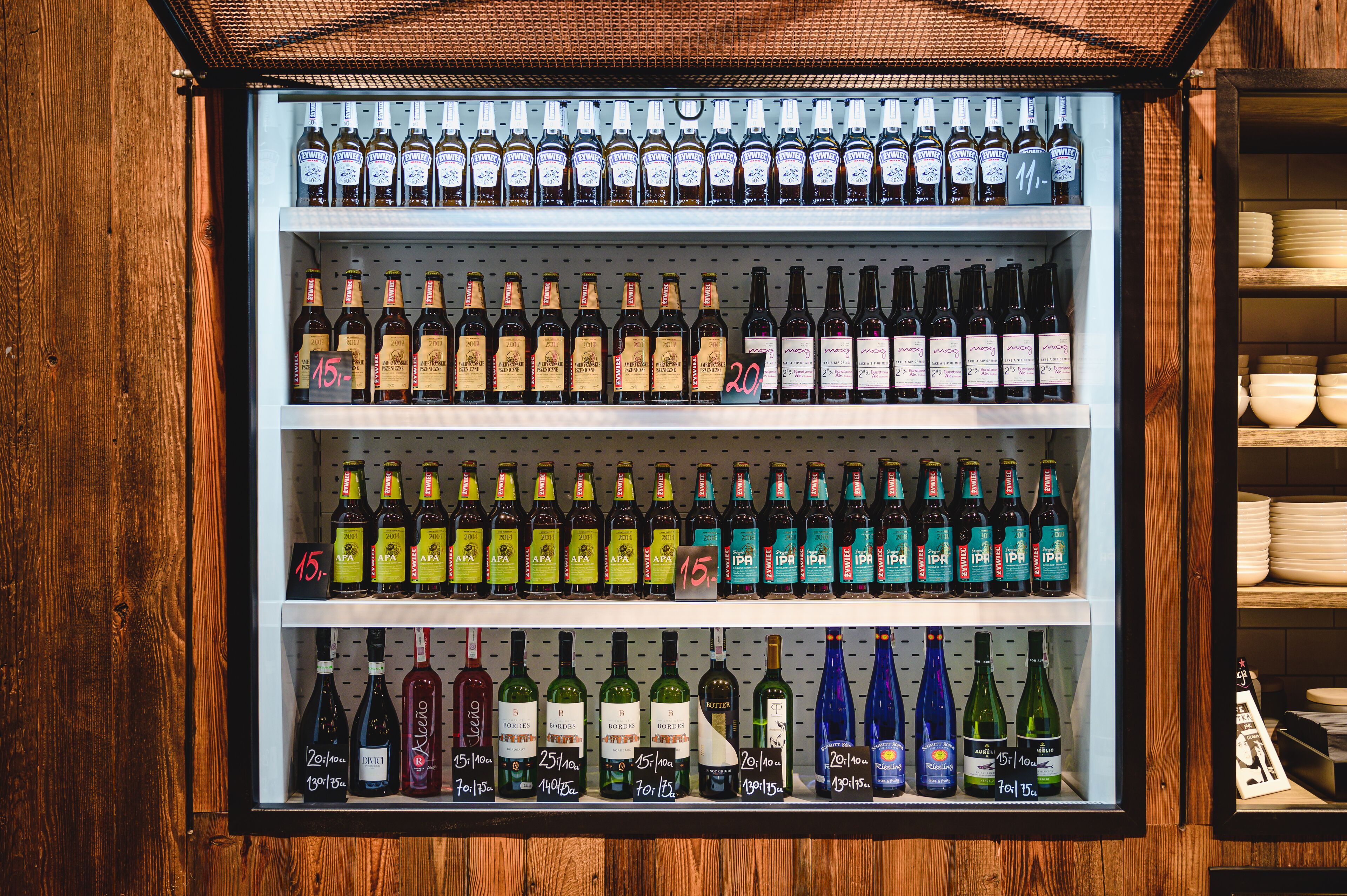 A refrigerated display case with various bottles of beverages, including wine and beer, arranged on shelves.