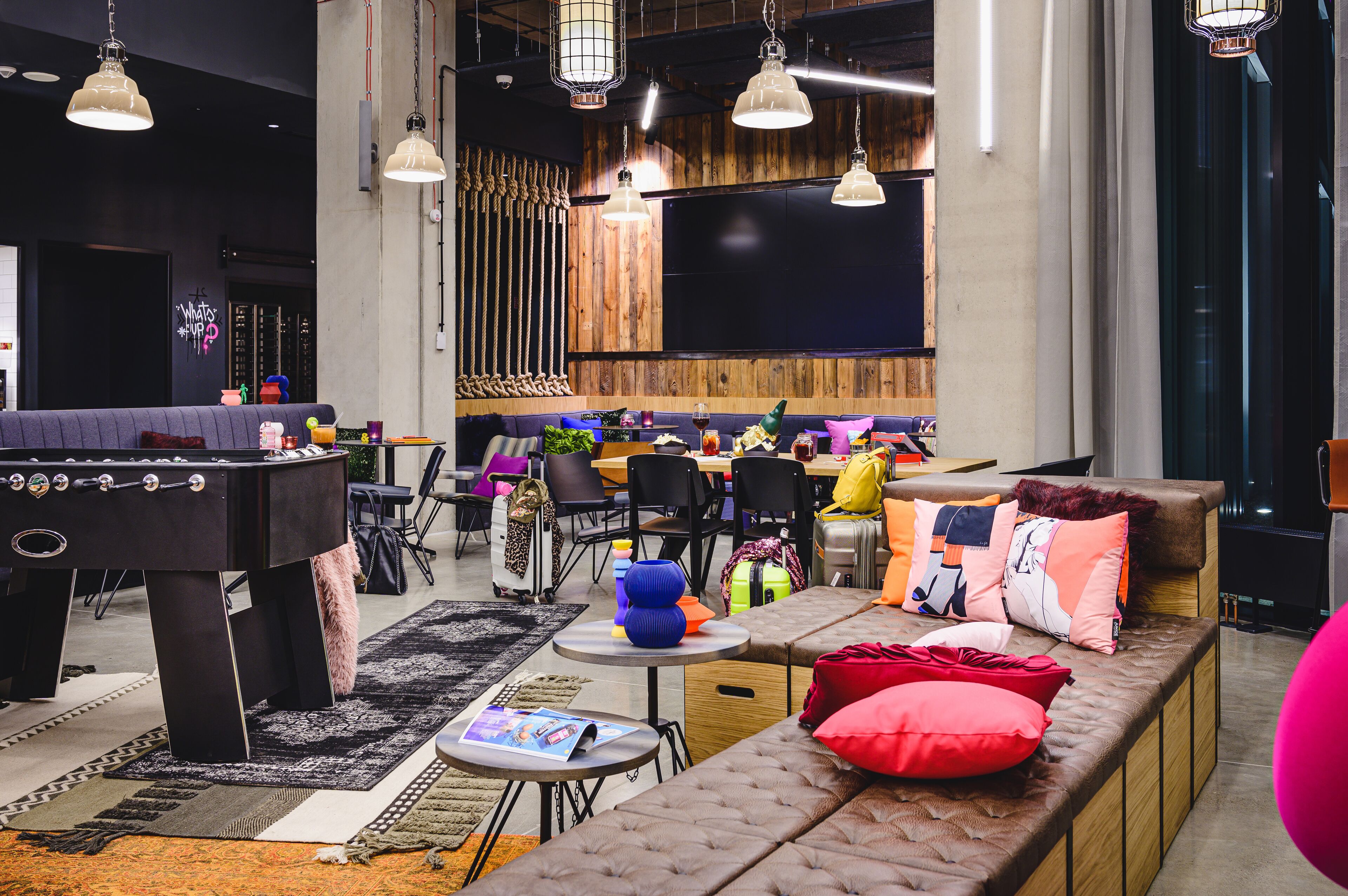 Un área de lounge moderna con mesa de fútbol, asientos cómodos y una zona de bar.
