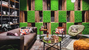 Een moderne woonkamer met een groene wand, een bruine bank, een ronde salontafel en een groene fauteuil.