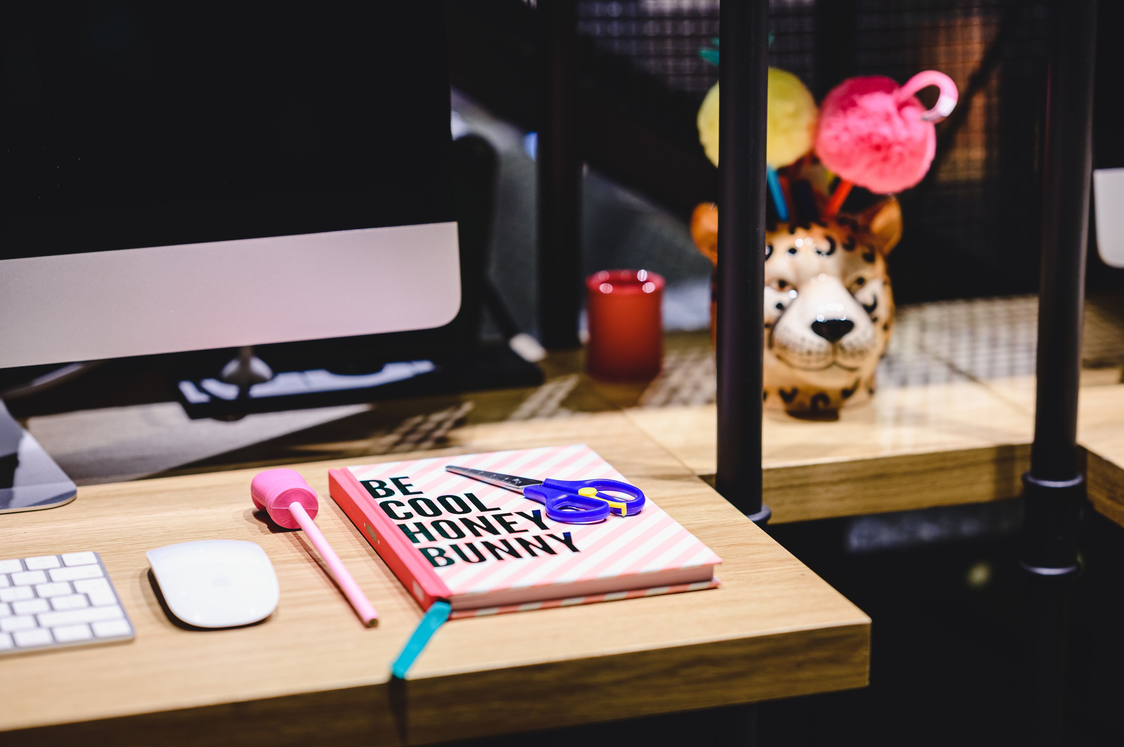 A desk with a keyboard, mouse, notebook, scissors, and a mug.